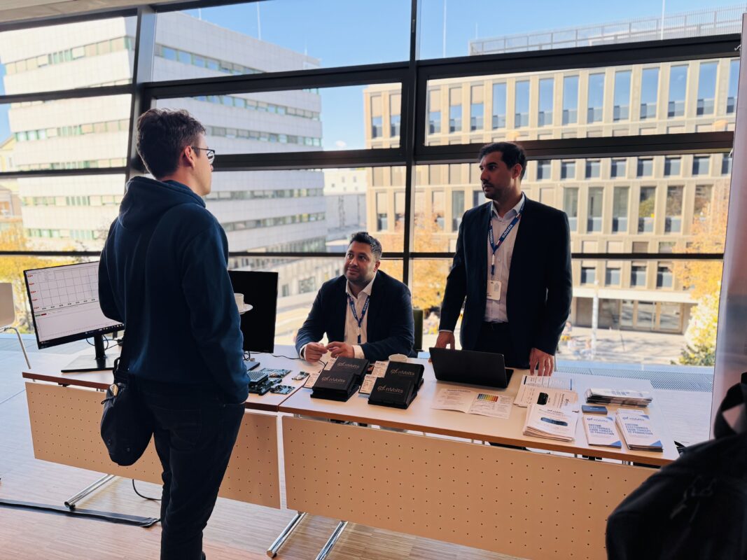 The nVolts team speaking with a visitor beside its electronic devices at MEMRISYS 2026 in Darmstadt
